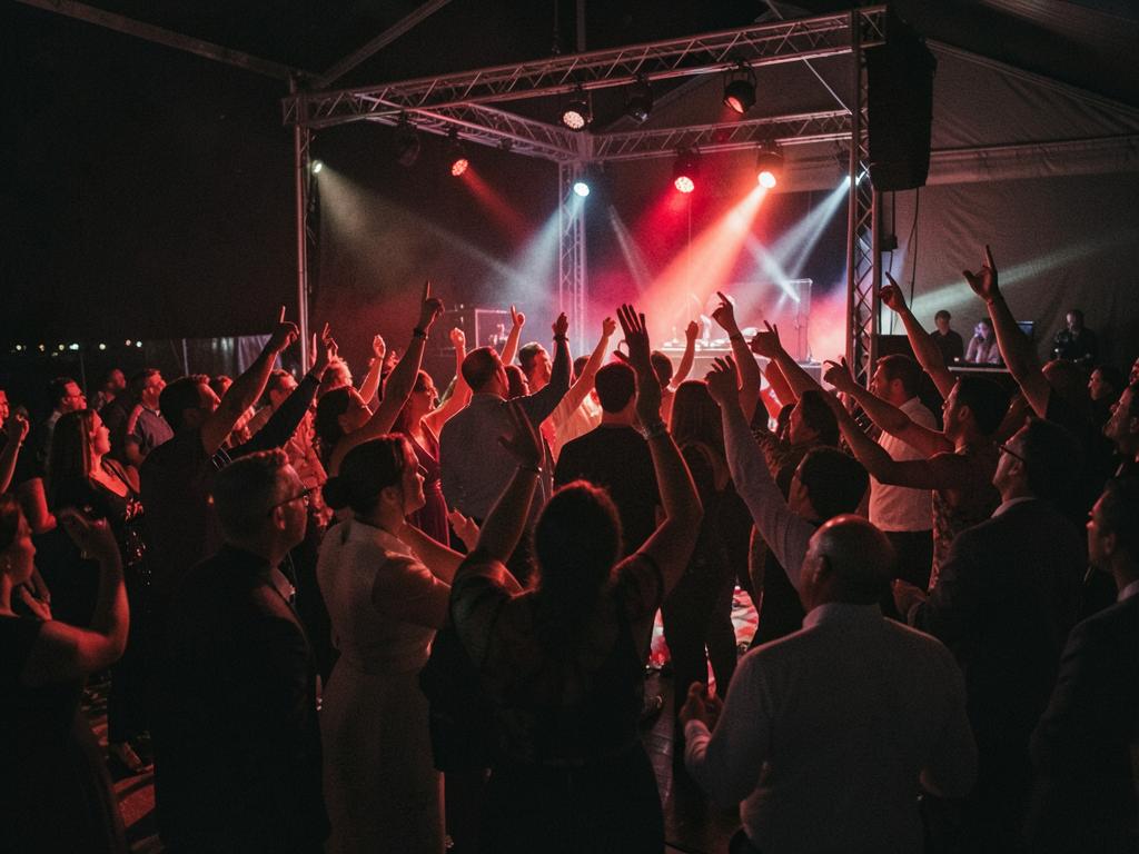 Packed wedding dance floor under red and white stage lighting